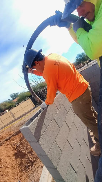 Father and Son Masonry worker laying CMU blocks for curved retaining wall at Bikini Beans Coffee Scottsdale AZ