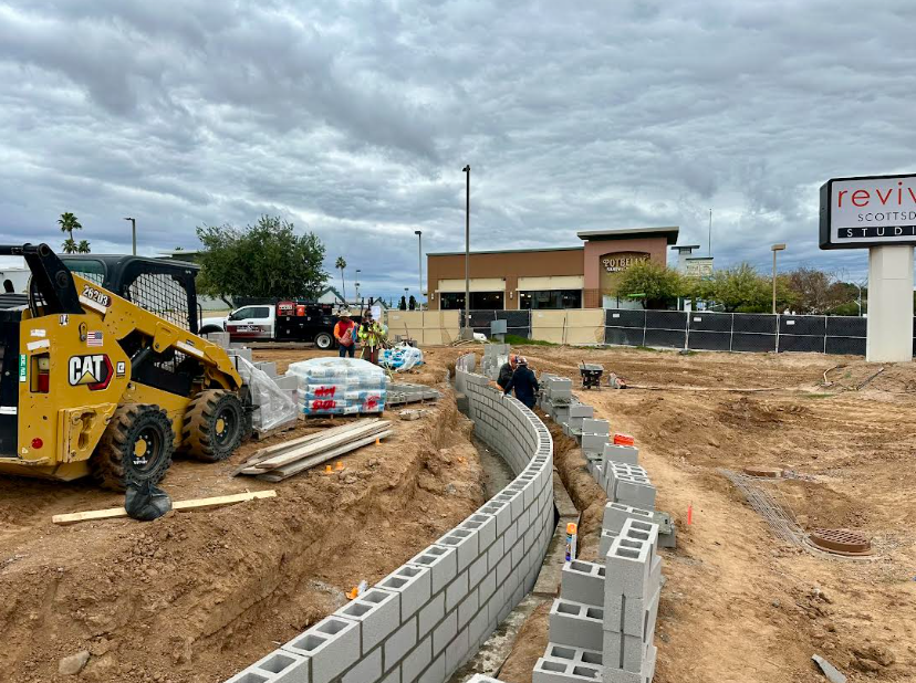 CAT skid steer and crew building curved CMU retaining wall at Bikini Beans Coffee Scottsdale AZ