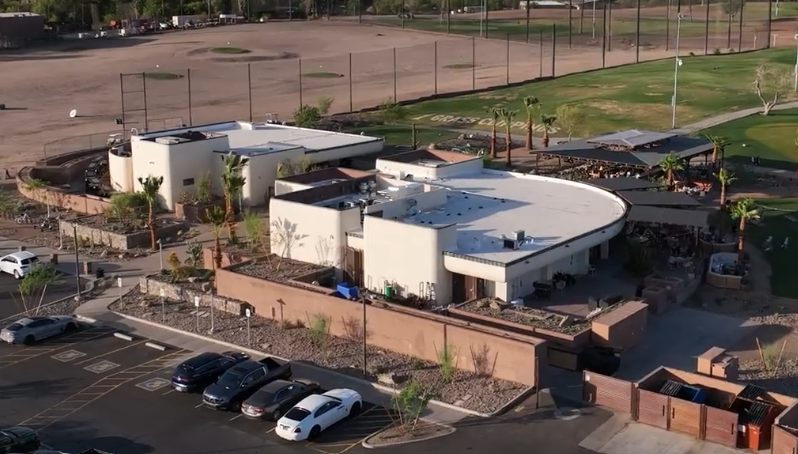 Aerial view of Grass Clippings Rolling Hills commercial building with masonry exterior and outdoor seating area Arizona