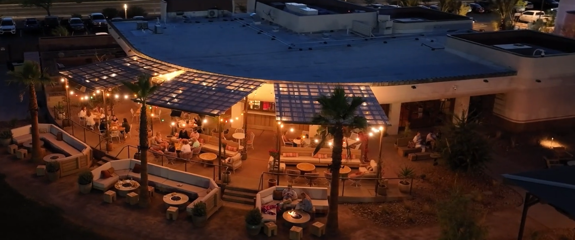 Night aerial view of Grass Clippings Rolling Hills outdoor patio with string lights and solar roof panels Arizona