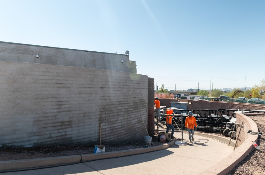 Father and Son Masonry crew applying stucco finish to curved brick perimeter wall at Grass Clippings Rolling Hills AZ