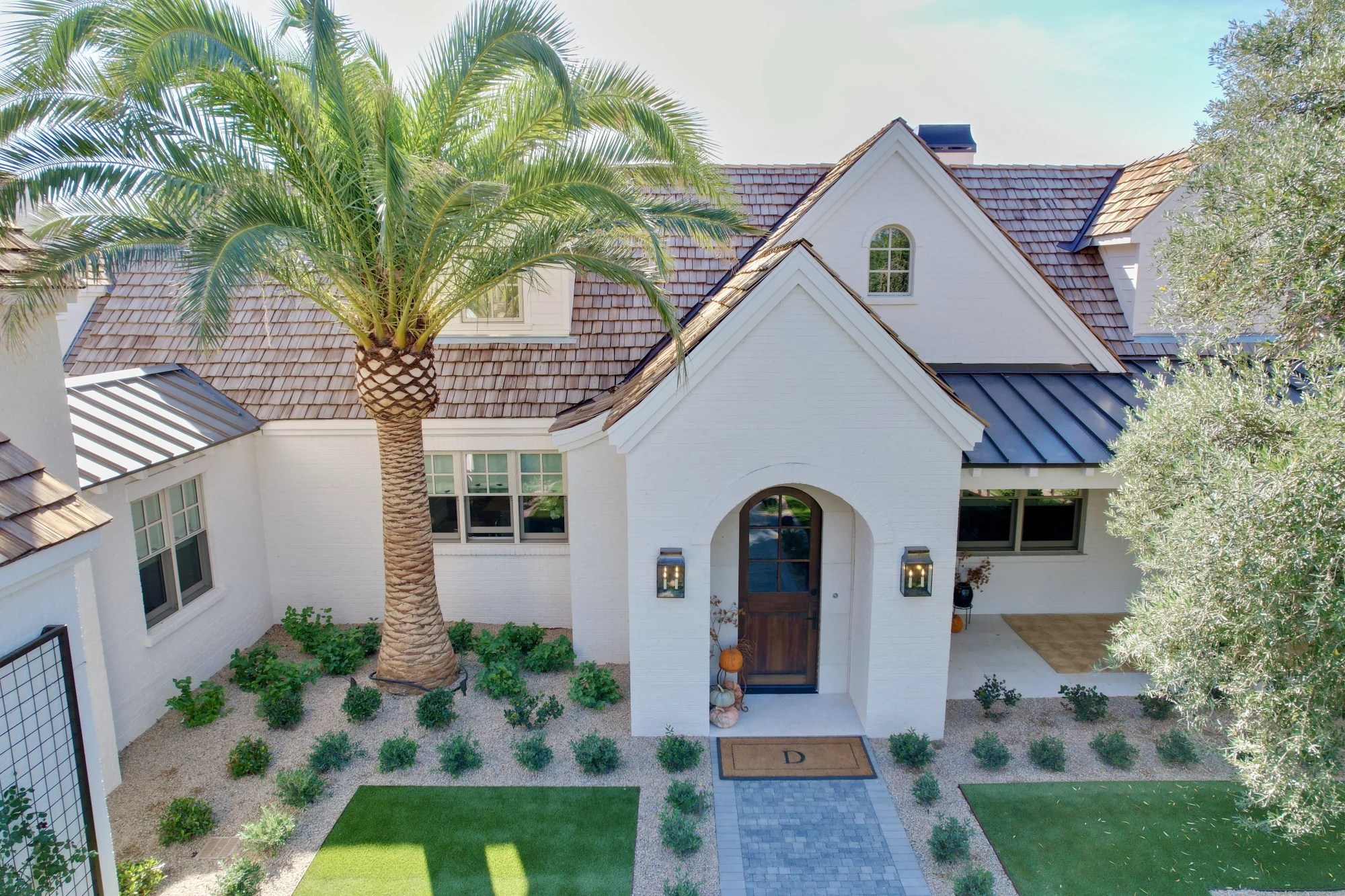 Side view of white brick residence with cedar shake roof and rose trellis accents in Phoenix AZ