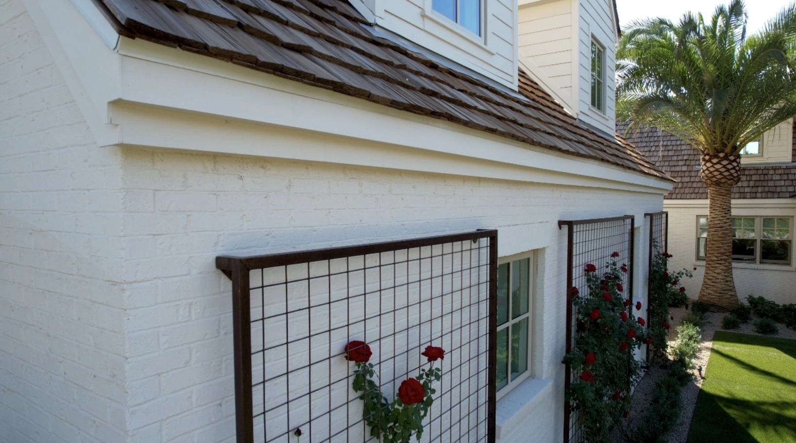 Close-up of painted brick wall with decorative iron trellis and climbing roses on residential home in Phoenix AZ